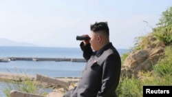 North Korean leader Kim Jong Un looks through a pair of binoculars during an inspection of the defense detachment on Ung Islet, in an undated photo released by North Korea's Korean Central News Agency on July 7, 2014.