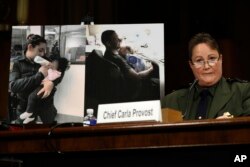 U.S. Border Patrol Chief Carla Provost testifies by a photo of agents taking care of children during a Senate Judiciary border security and immigration subcommittee hearing about the border, May 8, 2019.