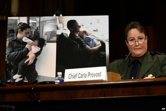 U.S. Border Patrol Chief Carla Provost testifies by a photo of agents taking care of children during a Senate Judiciary border security and immigration subcommittee hearing about the border, May 8, 2019.