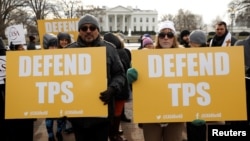 Demonstrators hold signs protesting the termination of Salvadorans' Temporary Protected Status