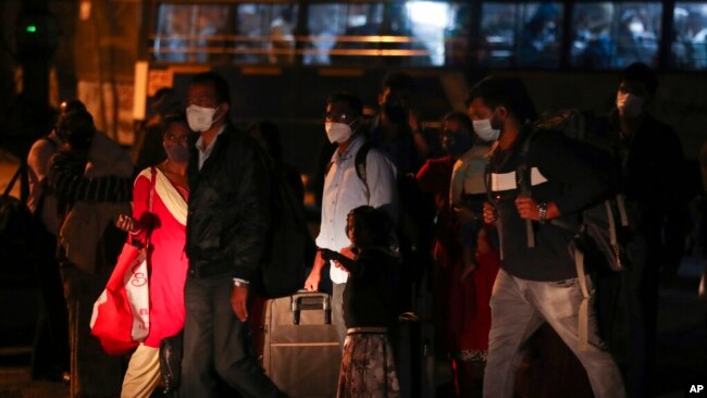 People wearing face masks as a precaution against the coronavirus wait for a bus in Hyderabad, India, Jan. 9, 2022.