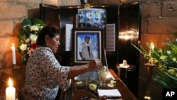 A woman dips a flower in a glass of water placed on the coffin of slain journalist Gumaro Perez during his wake in Acayucan, Veracruz state, Mexico, Dec. 20, 2017. 