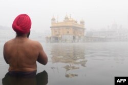 FILE - A devotee prays at the Sikh shrine the Golden Temple amid dense fog conditions in Amritsar, India.