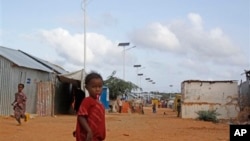 A Somali child stands under the solar powered lights at a refugee camp that were installed to help combat the rampant rapes that were occurring at night, in Mogadishu, Somalia, July 17, 2013.