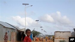 A Somali child stands under the solar powered lights at a refugee camp that were installed to help combat the rampant rapes that were occurring at night, in Mogadishu, Somalia, July 17, 2013.