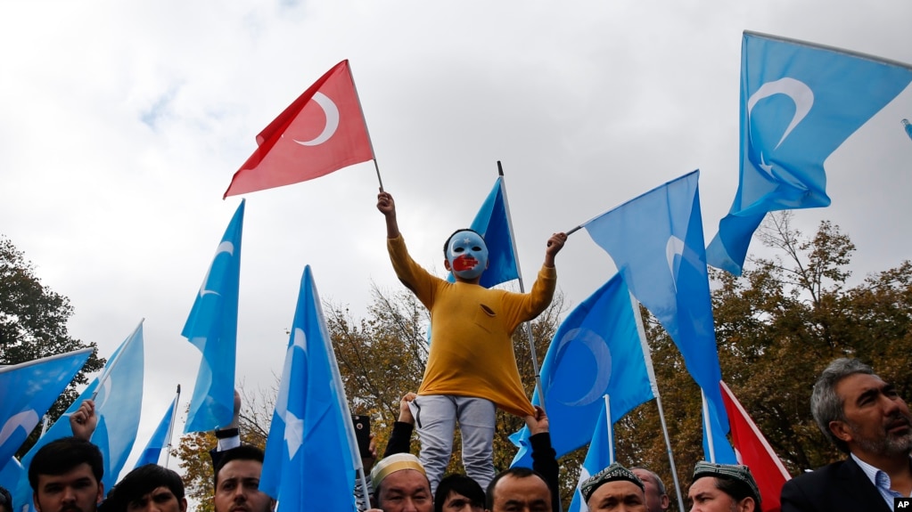 FILE - A child from the Uighur community living in Turkey, who is wearing a mask in the colors of the flag which ethnic Uighurs call East Turkestan and with a painted hand with the colors of China's flag, participates in a protest in Istanbul, Nov. 6, 2018.