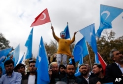 FILE - A child from the Uighur community living in Turkey, who is wearing a mask in the colors of the flag which ethnic Uighurs call East Turkestan and with a painted hand with the colors of China's flag, participates in a protest in Istanbul, Nov. 6, 2018, against alleged oppression by the Chinese government to Muslim Uighurs in the far-western Xinjiang province.