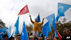 FILE - A child from the Uighur community living in Turkey, who is wearing a mask in the colors of the flag which ethnic Uighurs call East Turkestan and with a painted hand with the colors of China's flag, participates in a protest in Istanbul, Nov. 6, 2018.