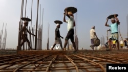 FILE - Laborers work at the construction site of a residential complex on the outskirts of Kolkata, India.