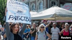 People attend a rally against planned increases to the nationwide pension age in Krasnodar, Russia, Sept. 9, 2018. The poster reads: "Pension age increase is a lifetime slavery."