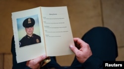 Seorang polisi Capitol memegang buku acara penghormatan mendiang Polisi Capitol Brian D. Sicknick, yang disemayamkan di Rotunda, Gedung Kongres, di Washington D.C., 3 Februari 2021. (Foto: Demetrius Freeman/Pool via Reuters)