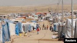 FILE - Syrian refugees, who fled violence back home, walk through the Domiz refugee camp in the northern Iraqi province of Dohuk, Aug. 21, 2013. 