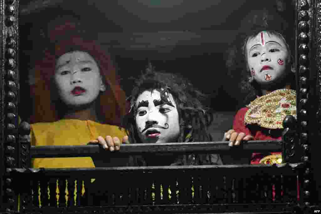 Young artists with painted faces look out of a window before their performance at Basantapur Durbar Square on the second to last day of the &#39;Indra Jatra&#39; Hindu festival in Kathmandu, Nepal, Sept. 16, 2019.