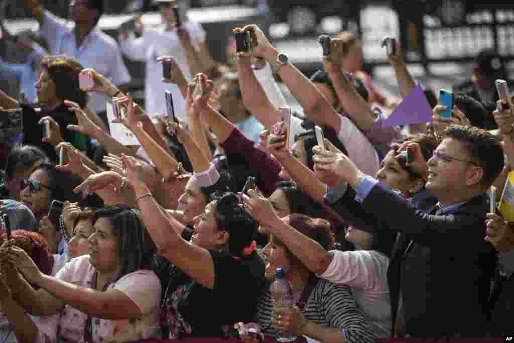 A crowd takes photos of Pope Francis as he arrives for a mid-morning prayer at the Shrine of Our Lord of the Miracles in Lima, Peru.