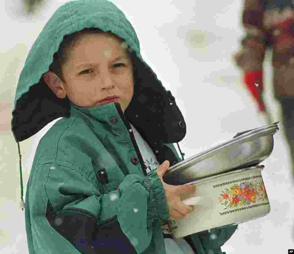 A young Turkish quake survivor holds empty saucepans waiting for food during a food distribution at a tent city near the northwest Turkish town of Duzce, January 26, 1999. (Reuters)