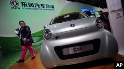 A visitor looks at an E30 EV, a small electric vehicle of Chinese state-owned automobile manufacturer Dongfeng Motor Co., at China International Industry Fair in Shanghai, Nov. 5, 2013. 
