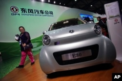 FILE - A visitor looks at an E30 EV, a small electric vehicle of Chinese state-owned automobile manufacturer Dongfeng Motor Co., at China International Industry Fair in Shanghai, Nov. 5, 2013.