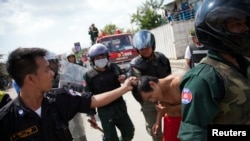 FILE - Security forces detain a man during clashes with garment workers in Phnom Penh, Cambodia, Nov. 12, 2013.