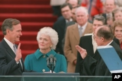 FILE - President George Bush raises his right hand as he is sworn into office as the 41st president of the United States as first lady Barbara Bush looks on, outside the west front of the Capitol, in Washington, Jan. 20, 1989.