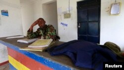 A policeman sits near the scene where his colleague was killed during an attack by gunmen who raided the police station in Gamba, Kenya, July 6, 2014. 
