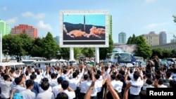 People watch a huge screen showing the test launch of intercontinental ballistic missile Hwasong-14 in this undated photo released by North Korea's Korean Central News Agency (KCNA), July 5, 2017.