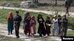 FILE - Afghan children hold the Quran as they go to a madrassa, or religious school, in Dand Ghori district in Baghlan province, Afghanistan, March 15, 2016.