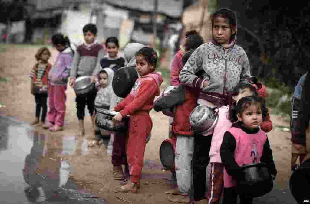 Palestinian children wait to receive a meal from donors in an impoverished neighborhood in Gaza City.