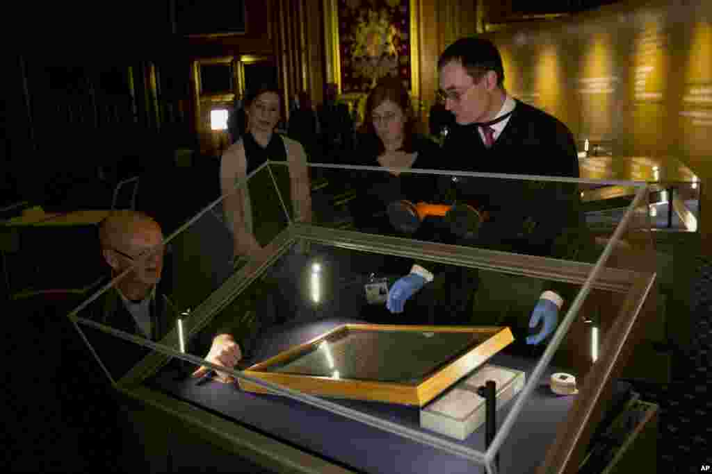 The Salisbury Cathedral 1215 copy of the Magna Carta is installed in a cabinet by Chris Woods, right, the director of the National Conservation Service in the Queen&#39;s Robing Room at the Houses of Parliament in London. It will be displayed alongside the other three surviving original parchment engrossments of the Magna Carta to mark the 800th anniversary of the sealing of Magna Carta at Runnymede in 1215, . The Magna Carta established the timeless principle that no individual, even a monarch, is above the law.