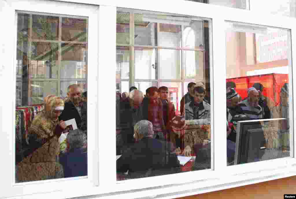 People are seen through a window as they register to vote at a polling station, during a presidential election in Dushanbe, Nov. 6, 2013.