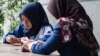 FILE - Women use their smart phones at a cafe in Jakarta, Jan. 3, 2018.