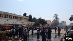 Des pompiers s'activent à éteindre le feu sur trois véhicules endommagés et partiellement incendiés à l'explosion d'une grenade près de la Banque commerciale Kenya à Bujumbura, Burundi vendredi 29 mai 2015. (Edward Rwena - VOA
