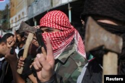 Маскиран Палестинец во Рафа, Појасот Газа, го слави нападот врз синагогата во Ерусалим