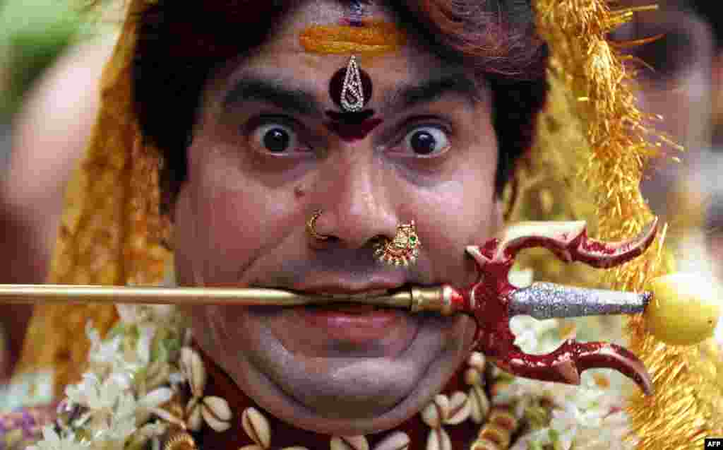 An Indian Hindu male devotee dressed as a woman dances during the festival of &quot;Bonalu&quot;, a ritual offering to the goddess Kali, at the Sri Ujjaini Mahakali Temple in Secunderabad.