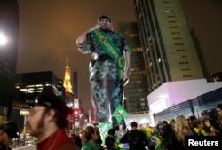 Partidarios del Jair Bolsonaro, candidato presidencial del Partido Social Liberal, junto a un gigante muñecor que reresenta al candidato de Bolsonaro a la vicepresidencia Hamilton Mourao, en Sao Paulo, Brasil, el domingo, 7 de octubre de 2018.