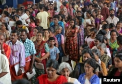 Flood-affected people wait to receive food inside a college auditorium, which has been converted into a temporary relief camp, in Kochi in the southern state of Kerala, India, Aug. 20, 2018.