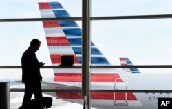 FILE - A passenger talks on the phone as American Airlines jets sit parked at their gates at Washington's Ronald Reagan National Airport, Jan. 25, 2016. Numbers provided by U.S. Customs and Border Protection show a fivefold increase in electronic media searches in fiscal 2016 over the previous year.