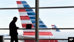 In this file photo, a passenger talks on the phone as American Airlines jets sit parked at their gates at Washington's Ronald Reagan National Airport, Jan. 25, 2016. (AP Photo/Susan Walsh, File)