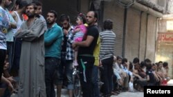 People line up for bread in the rebel-held al-Shaar neighborhood of Aleppo, Syria, July 14, 2016. 