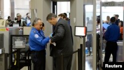 FILE An airline passenger is patted down by a TSA agent after passing through a full-body scanner at Los Angeles International Airport in Los Angeles, California, Feb. 20, 2014. The TSA is under fire as waiting periods for passenger screenings grow.