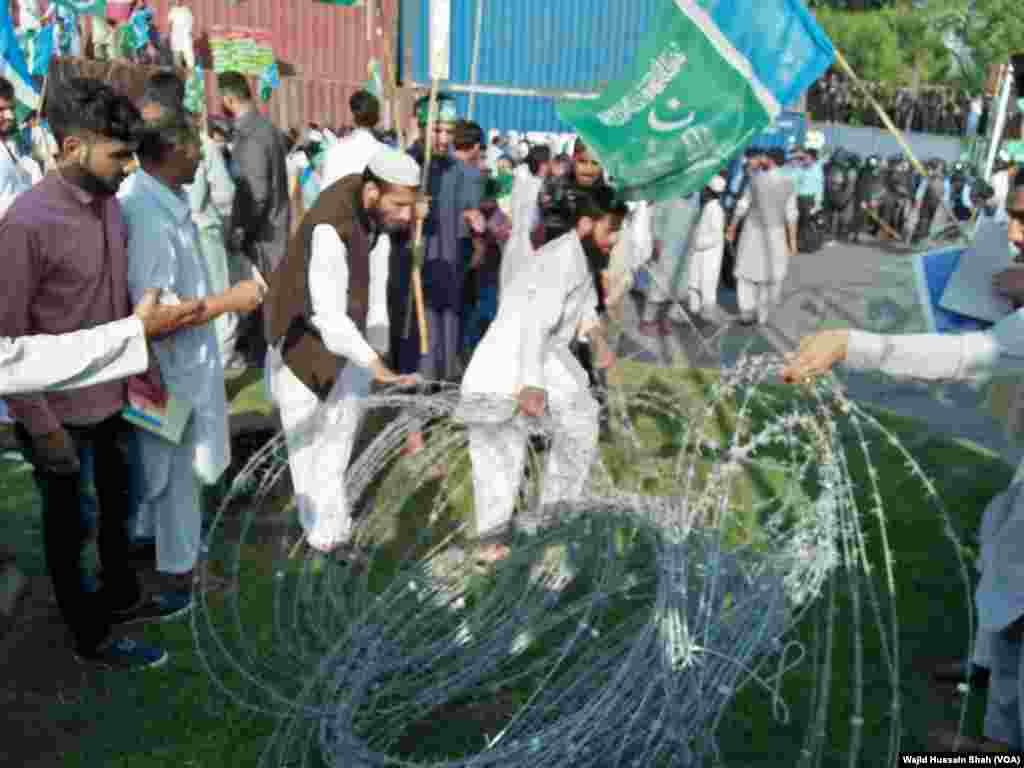 اسلام آباد میں مظاہرے کے شرکا پولیس کی جانب سے لگائے گئے خاردار تار ہٹانے کی کوشش کر رہے ہیں تاکہ میانمار کے سفارت خانے کی جانب مارچ کرسکیں۔