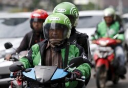 Seorang pengemudi dan penumpang naik sepeda motor, bagian dari layanan naik-naik Go-Jek, di jalan yang sibuk di Jakarta Pusat, 18 Desember 2015. (Foto: Reuters)