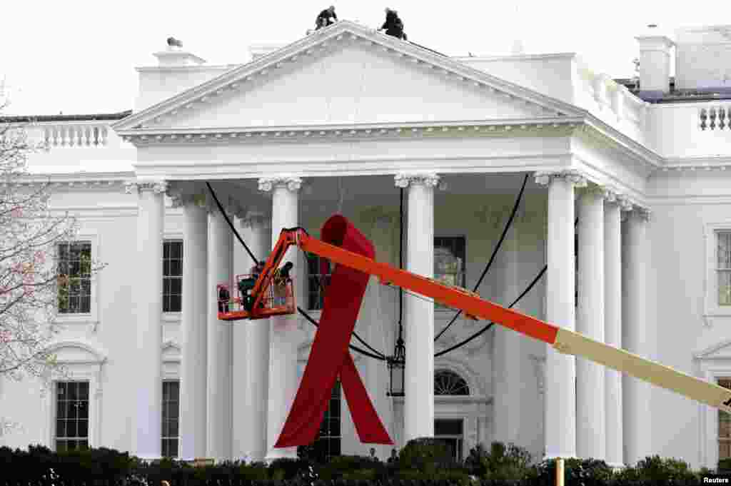 A large red ribbon is installed on the North Portico of the White House in Washington, November 30, 2012.