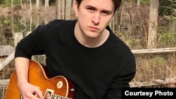 Seamus Hawks, a student of the Berklee College of Music and member of Students With Psychosis, poses with his guitar.