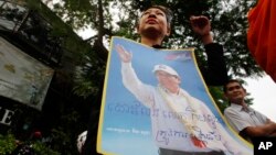 A supporter of the former opposition Cambodia National Rescue Party holds a poster of party leader Kem Sokha as she stands during a protest rally at a blocked street near the Appeals Court where party leader Kem Sokha is to appear, in Phnom Penh, Cambodia, Tuesday, March 27, 2018. The court on Tuesday is planning to hear a bail request for Kem Sokha who has been charged with treason. (AP Photo/Heng Sinith)