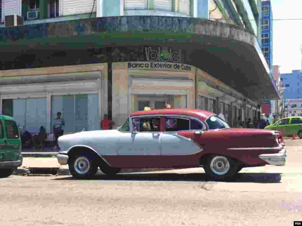 A bank in the center of Havana where people gather around "La Rampa," one of the new WiFi spots in the city, Aug. 13, 2015. (Celia Mendoza/VOA)