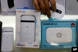 vA worker takes a Huawei mobile Internet device next to it competitor ZTE Corp, left, which are displayed for sale at a computer mall in Beijing Wednesday, July 4, 2018.