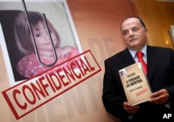 FILE- Former detective Goncalo Amaral poses with his book, July 24, 2008, whose title translates as "The Truth in the Lies," during its launch in Lisbon. Amaral says in the book he is convinced that Madeleine McCann died in the vacation apartment from where she went missing.