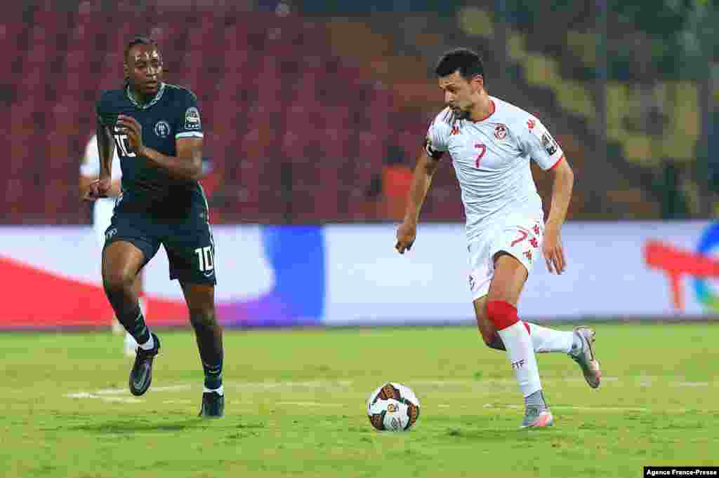Tunisia&#39;s forward Youssef Msakni (R) runs with the ball next to Nigeria&#39;s midfielder Joe Aribo during the round of 16 football match between Nigeria and Tunisia in Garoua, Cameroon on Jan. 23, 2022.