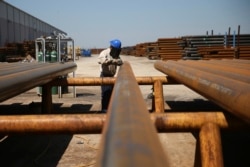 FILE - Jose Mata grinds a steel pipe at the Borusan Mannesmann plant in Baytown, Texas, April 23, 2018.