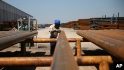 FILE - Jose Mata grinds a steel pipe at the Borusan Mannesmann plant in Baytown, Texas, April 23, 2018. The United States announced on March 22, 2022, an agreement with Britain to end tariffs on steel and aluminum imports.